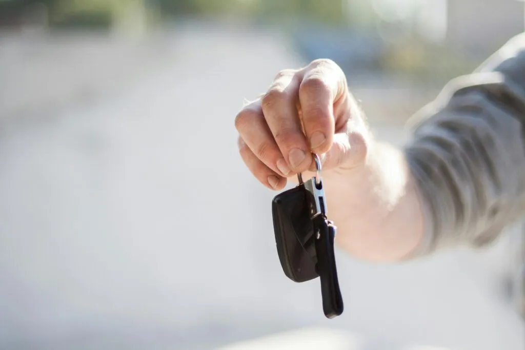 หน้าหลัก 21 Close-up of a hand handing over car keys, signifying purchase or rental.